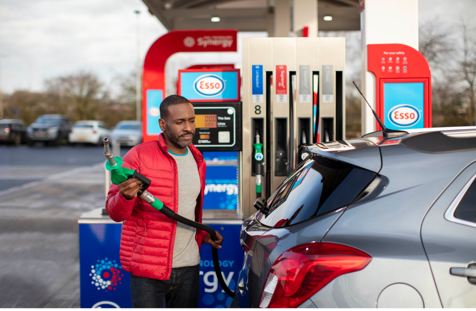 Man at Esso fuel station approaching car to fuel up